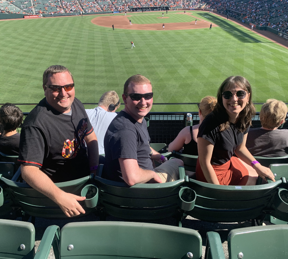 Three Brown Plus team members in seats at a baseball stadium