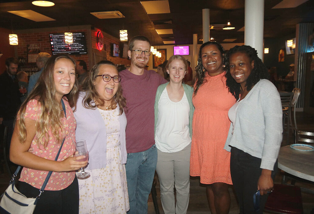 A group of six Brown Plus team members smiling together at a casual event