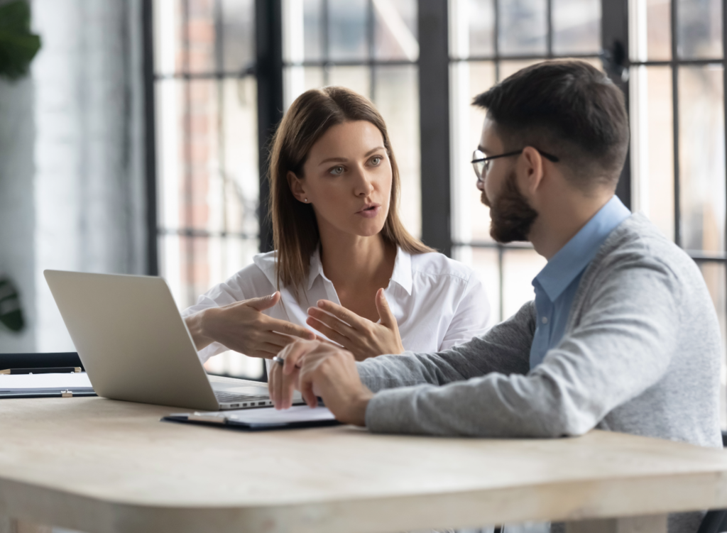 Woman on a laptop talking to a man working on a tablet