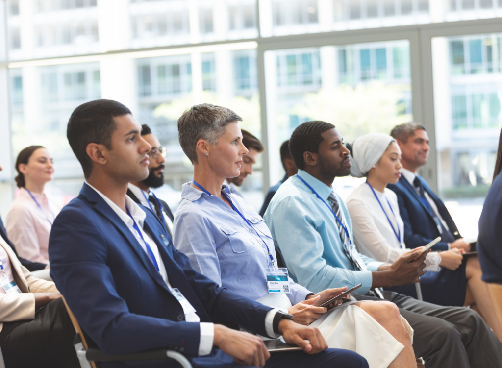 People sitting in chairs viewing a presentation at an event