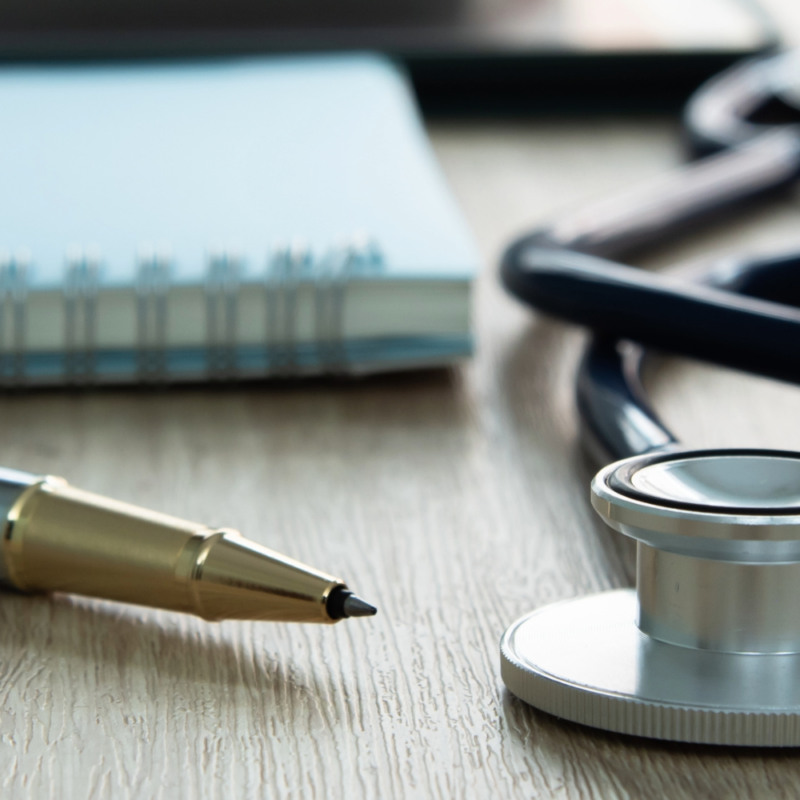 Stethoscope, pen and notebook on a table