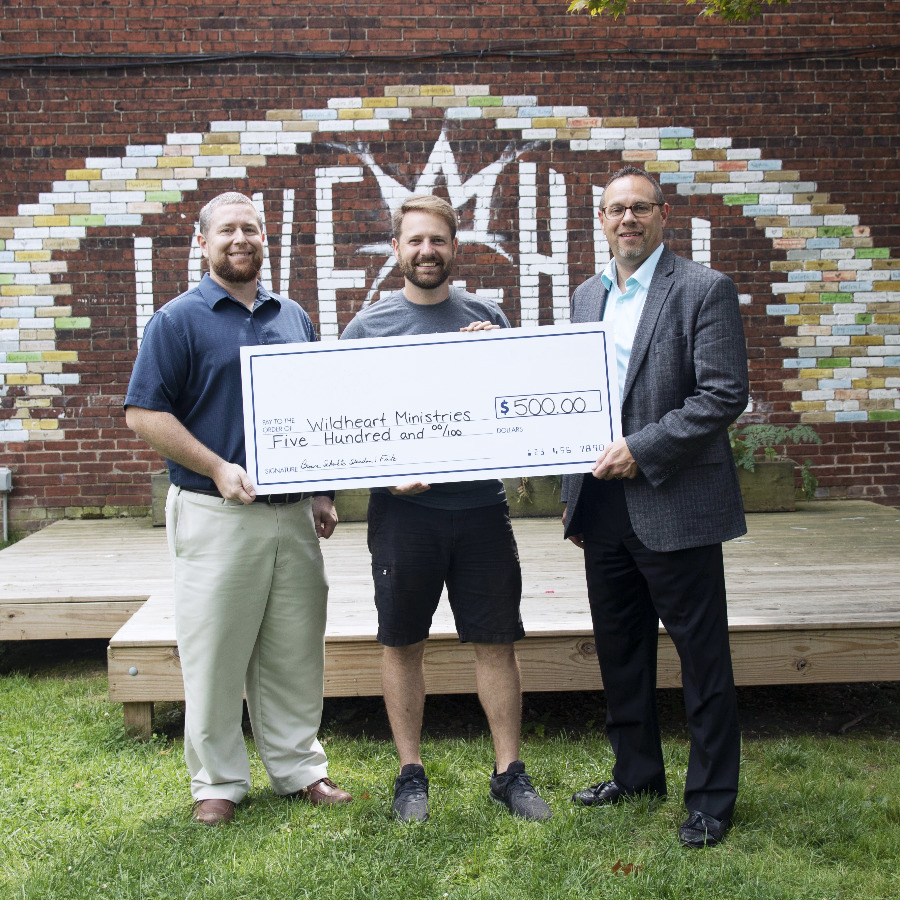 Three people holding an oversized check