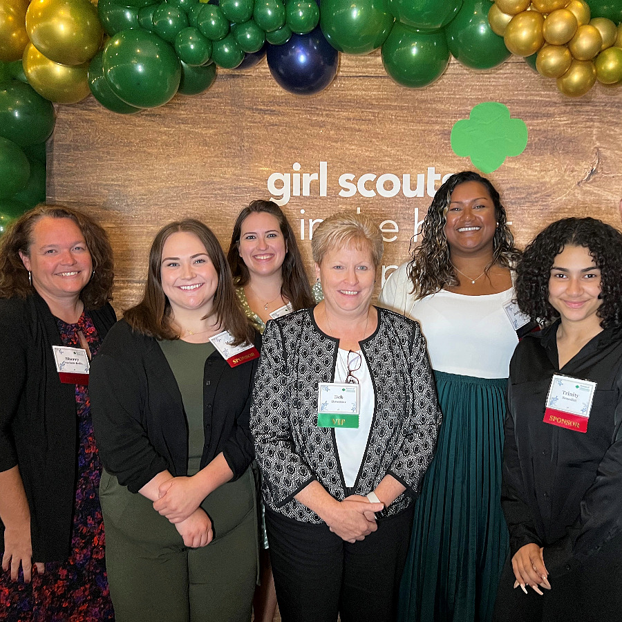 Group of Brown Plus Team Members in front of the girl scout logo at an event