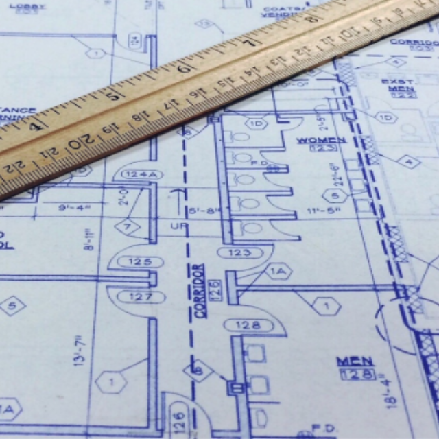 A wooden ruler laying on top of a structure blueprint