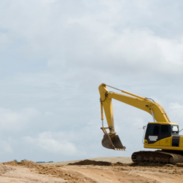 A yellow backhoe machine scoping sand or dirt
