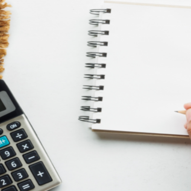 Hands using a calculator and holding a pencil over a blank notepad