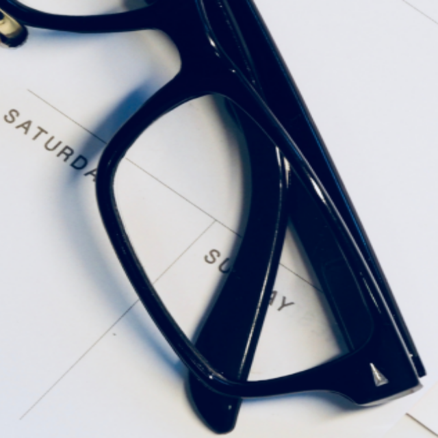 black rimmed glasses on top of a ring notebook