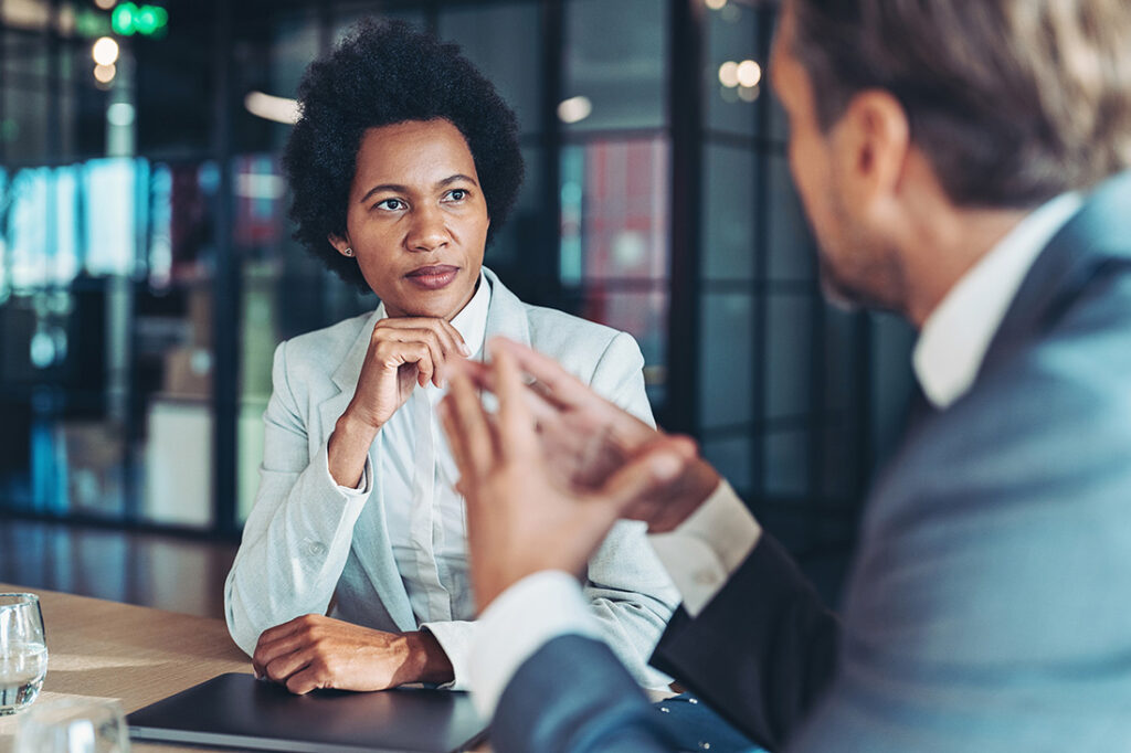 A woman with her hand under her chin looking at someone talking